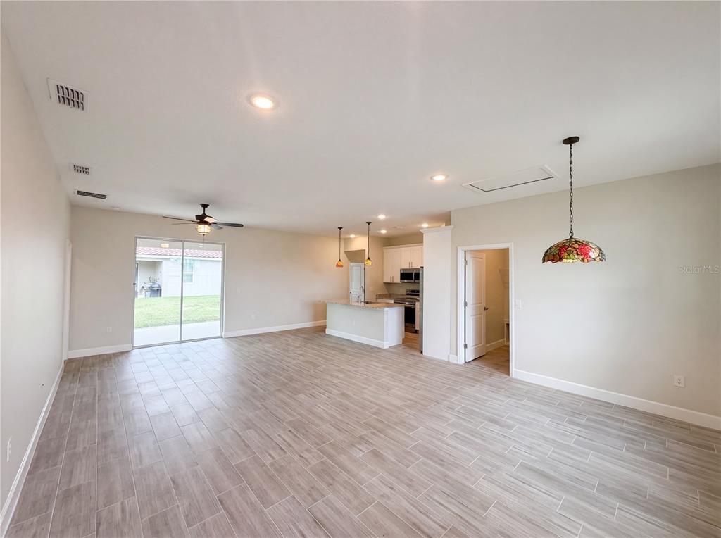 An open-concept living and dining area features light wood-look tile flooring and a kitchen island — 446 CINNAMON DRIVE, KISSIMMEE, FL
