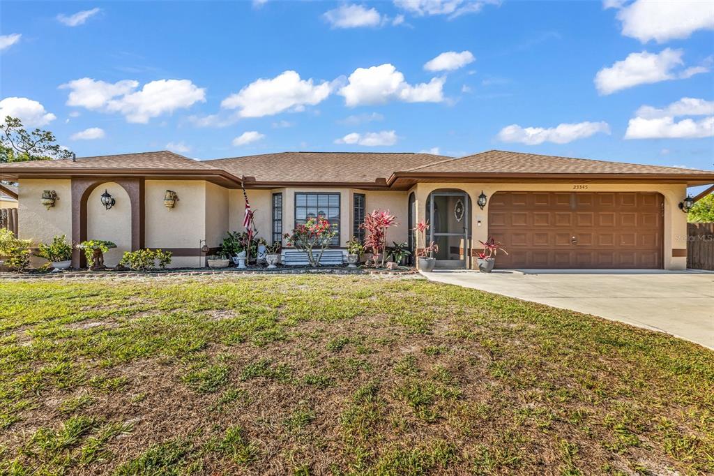 A single-story house with a brown roof, beige stucco exterior, and an attached two-car garage — 23345 FERNDALE AVENUE, PUNTA GORDA, FL