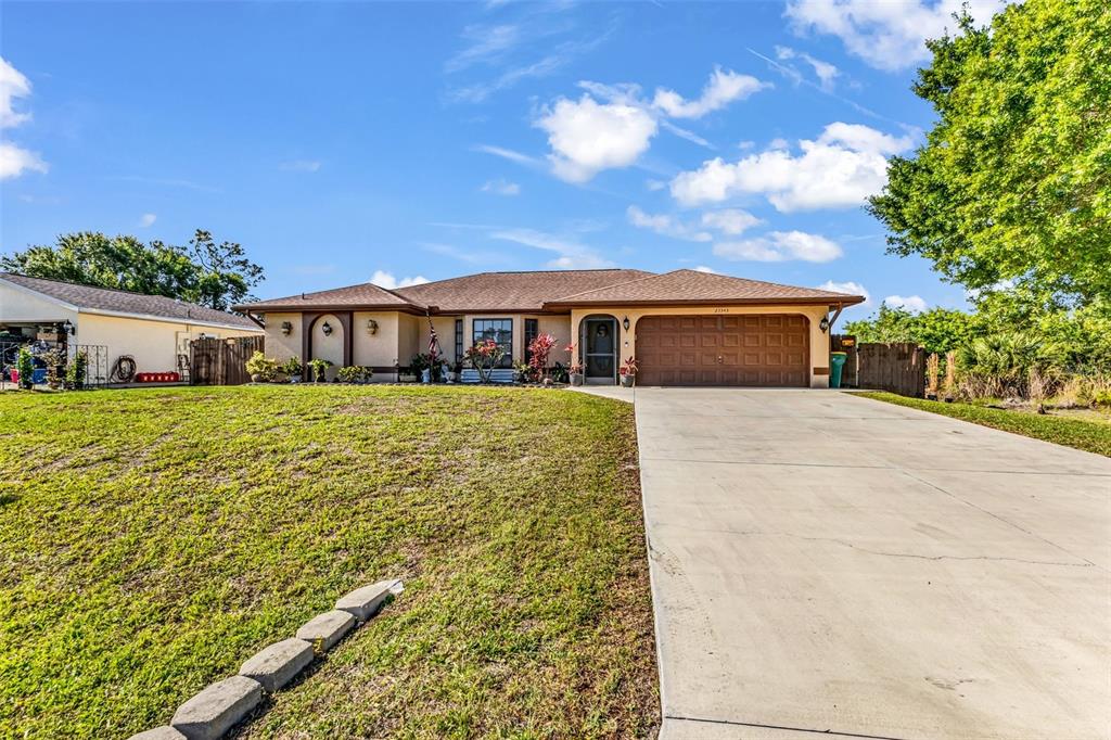 A single-story house with a brown roof, tan stucco exterior, and a concrete driveway — 23345 FERNDALE AVENUE, PUNTA GORDA, FL