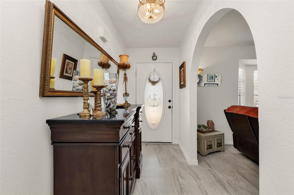 A foyer features a dark wood console table, a large wall mirror, and an arched entryway — 23345 FERNDALE AVENUE, PUNTA GORDA, FL