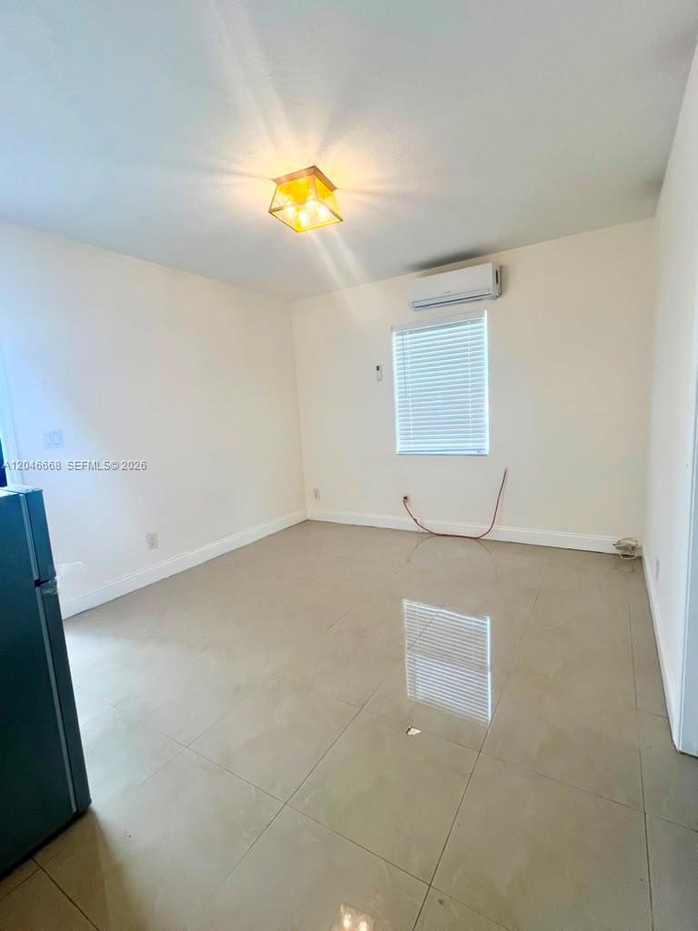 This room features light-colored tile flooring, a ceiling light fixture, and a wall-mounted air conditioner — HOLLYWOOD, FL
