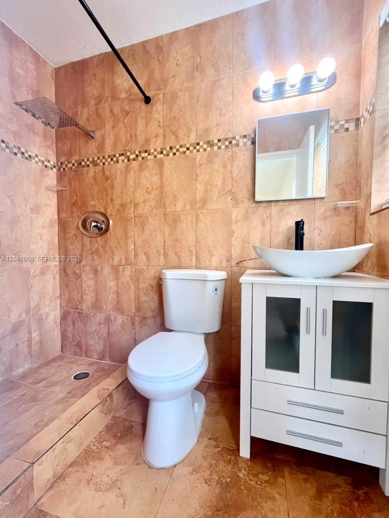 A bathroom features a walk-in shower, a white toilet, and a vessel sink vanity — HOLLYWOOD, FL
