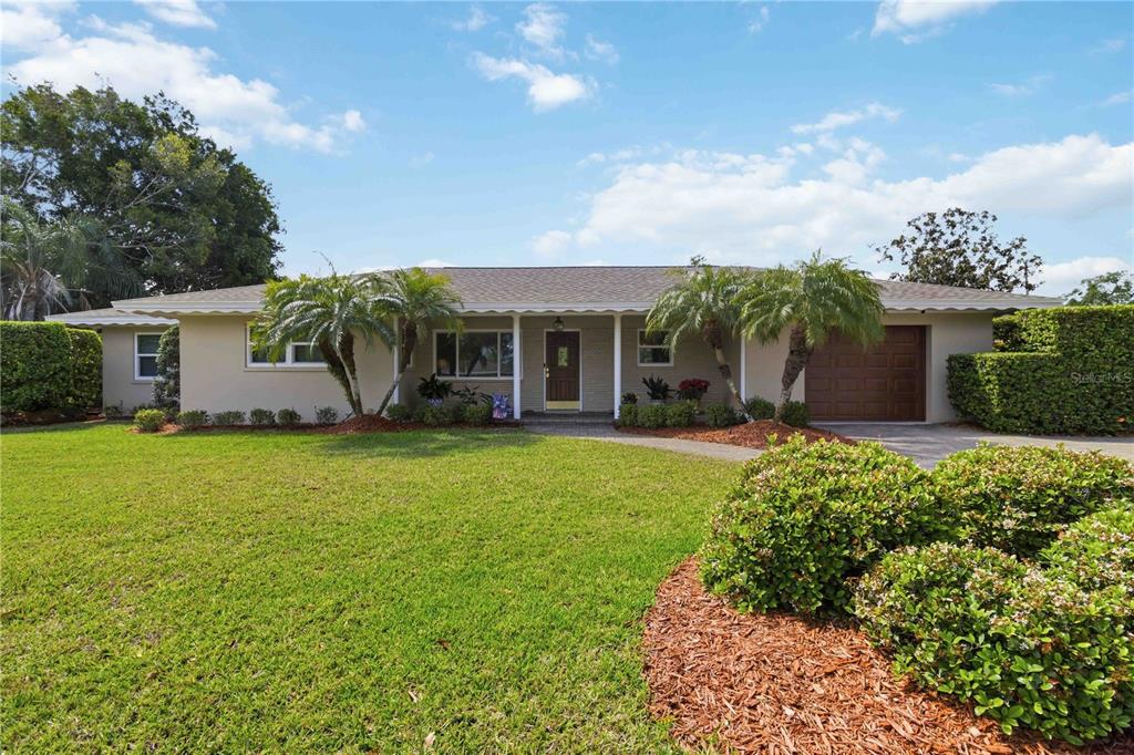 A single-story house with a tan exterior, a brown garage door, and a manicured lawn — 2068 SUNNYSIDE LANE, SARASOTA, FL