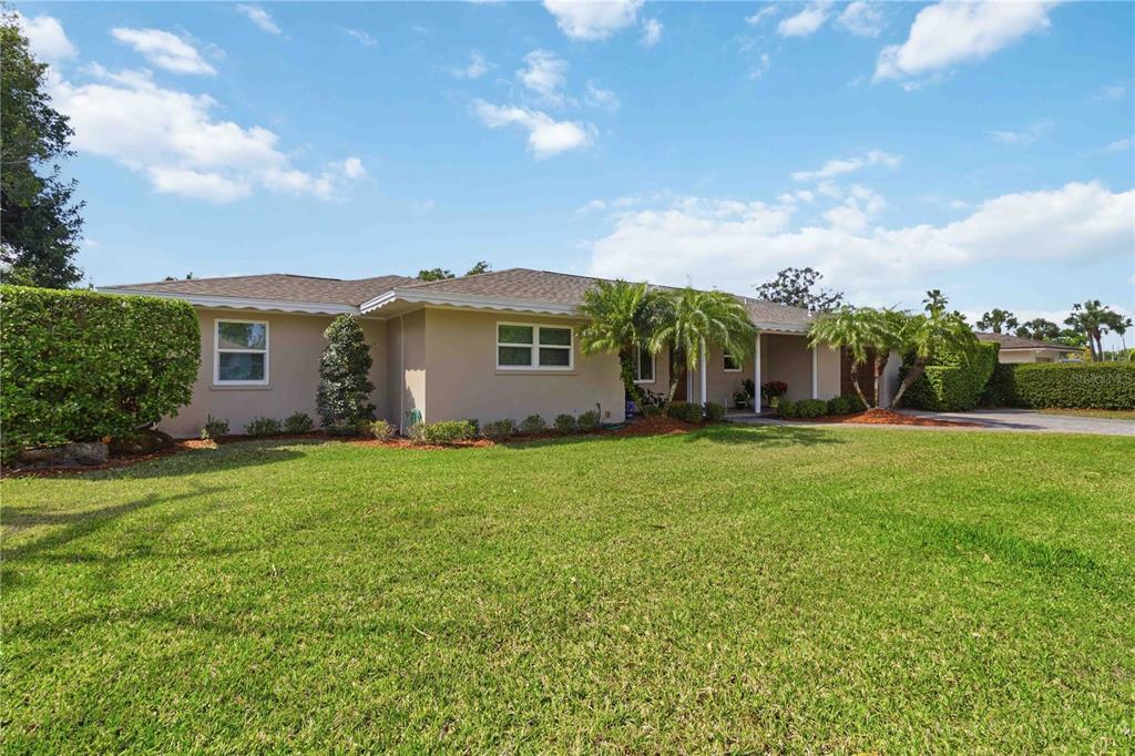 A single-story house with a beige exterior, a large front lawn, and several palm trees — 2068 SUNNYSIDE LANE, SARASOTA, FL
