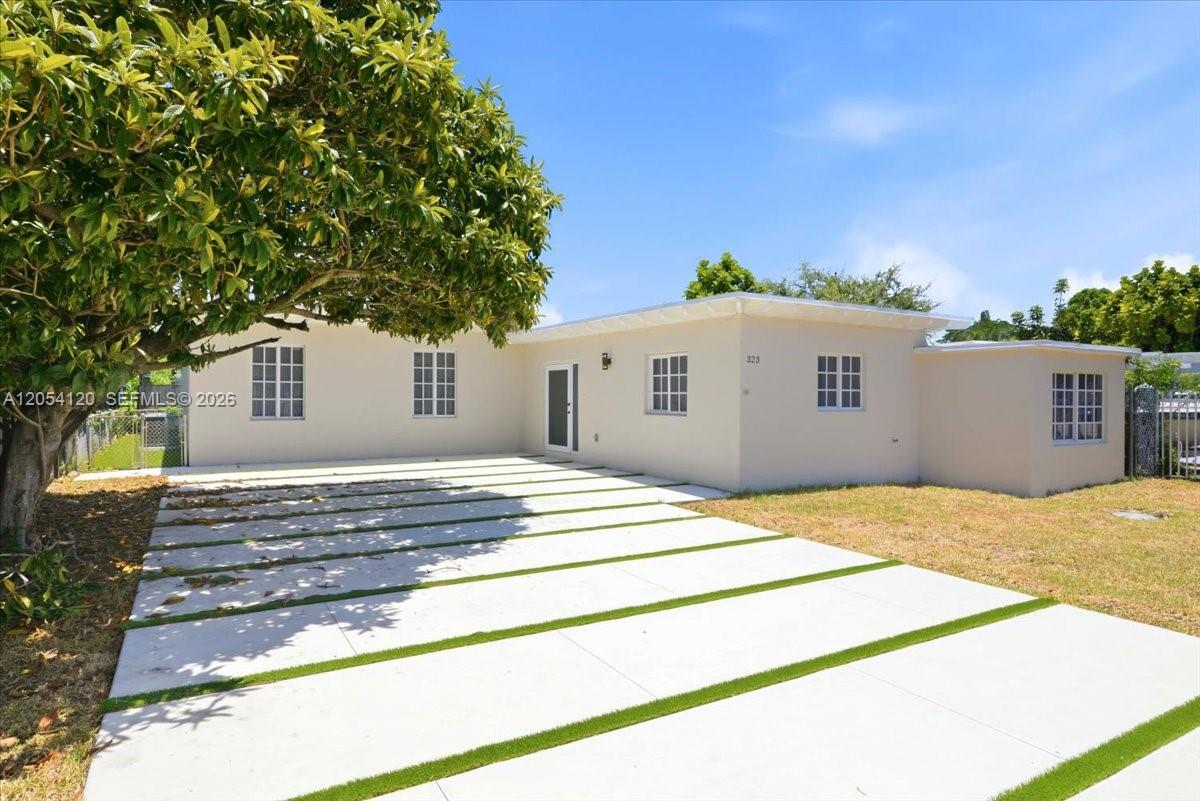 A single-story house with a white exterior and a concrete driveway with grass strips — 323 NW 104th Ter, Miami FL 33150, MIAMI, FL