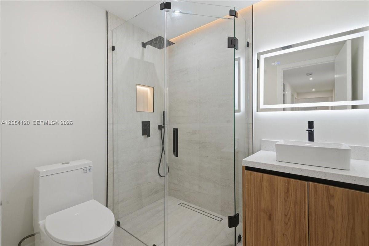 A modern bathroom features a glass-enclosed walk-in shower, a white vessel sink, and a toilet — 323 NW 104th Ter, Miami FL 33150, MIAMI, FL