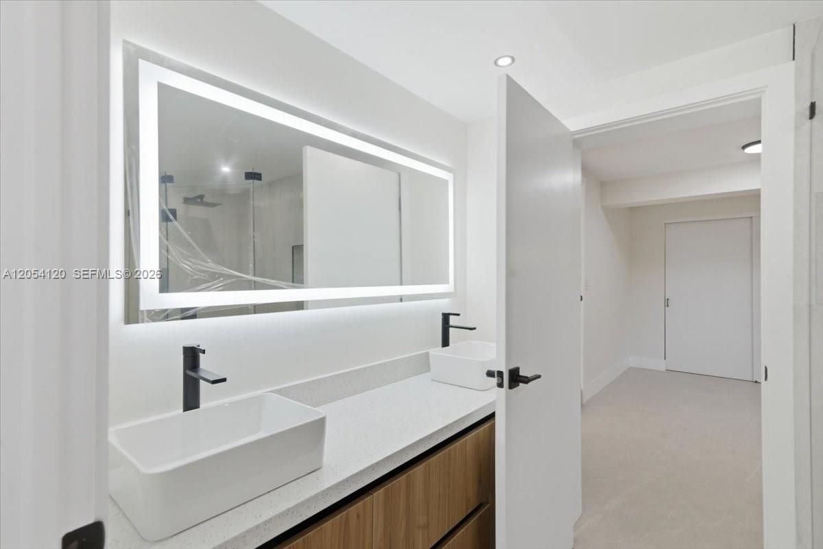 A modern bathroom features a double vanity with vessel sinks and a large LED mirror — 323 NW 104th Ter, Miami FL 33150, MIAMI, FL