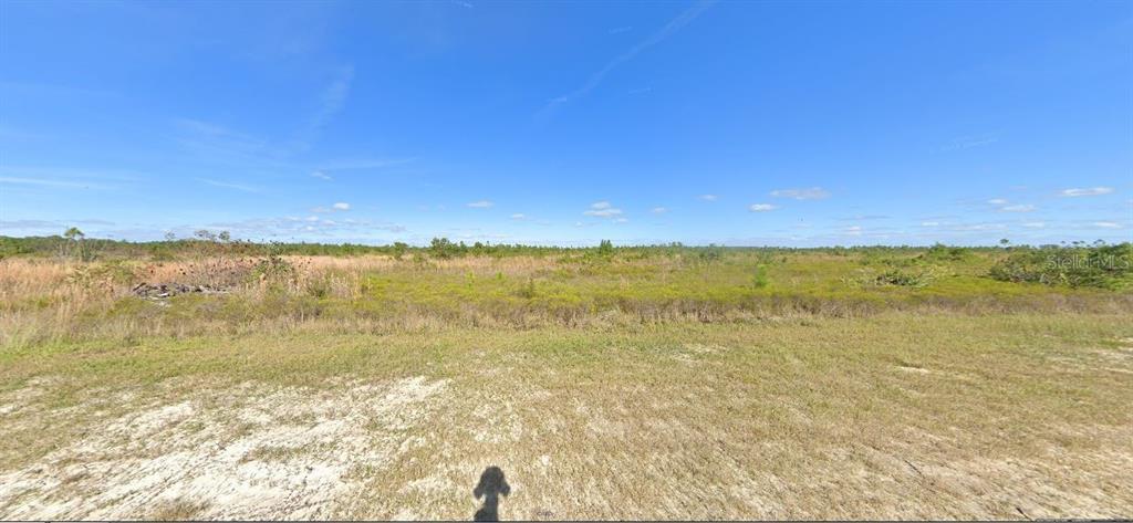 A wide, flat, grassy, and undeveloped plot of land under a clear blue sky — 424 PORTULACA DRIVE, INDIAN LAKE ESTATES, FL