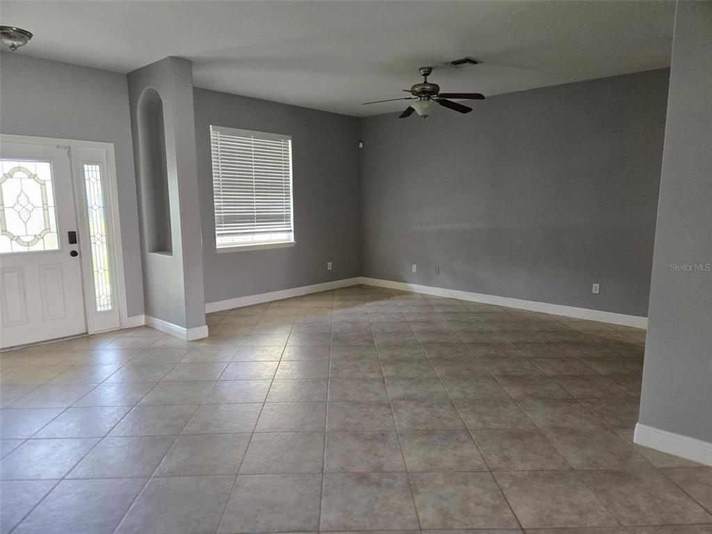 An empty room features gray walls, tile flooring, a ceiling fan, and a front door — 2739 ATWATER DRIVE, NORTH PORT, FL