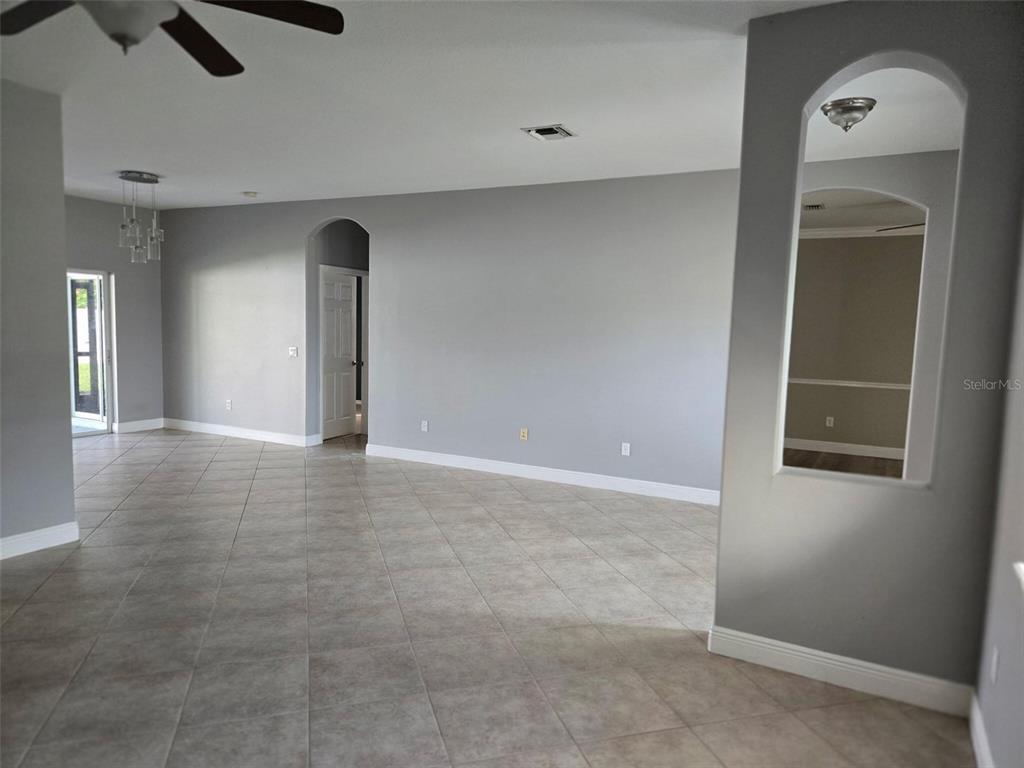 An open-concept living area features gray walls, tile flooring, and an arched wall cutout — 2739 ATWATER DRIVE, NORTH PORT, FL
