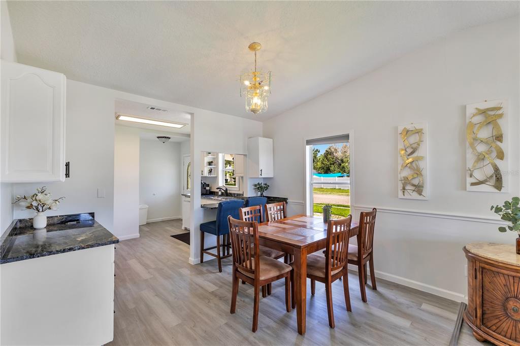 A dining area with a wooden table, chairs, and a view into the kitchen — 704 S CLYDE AVENUE, KISSIMMEE, FL