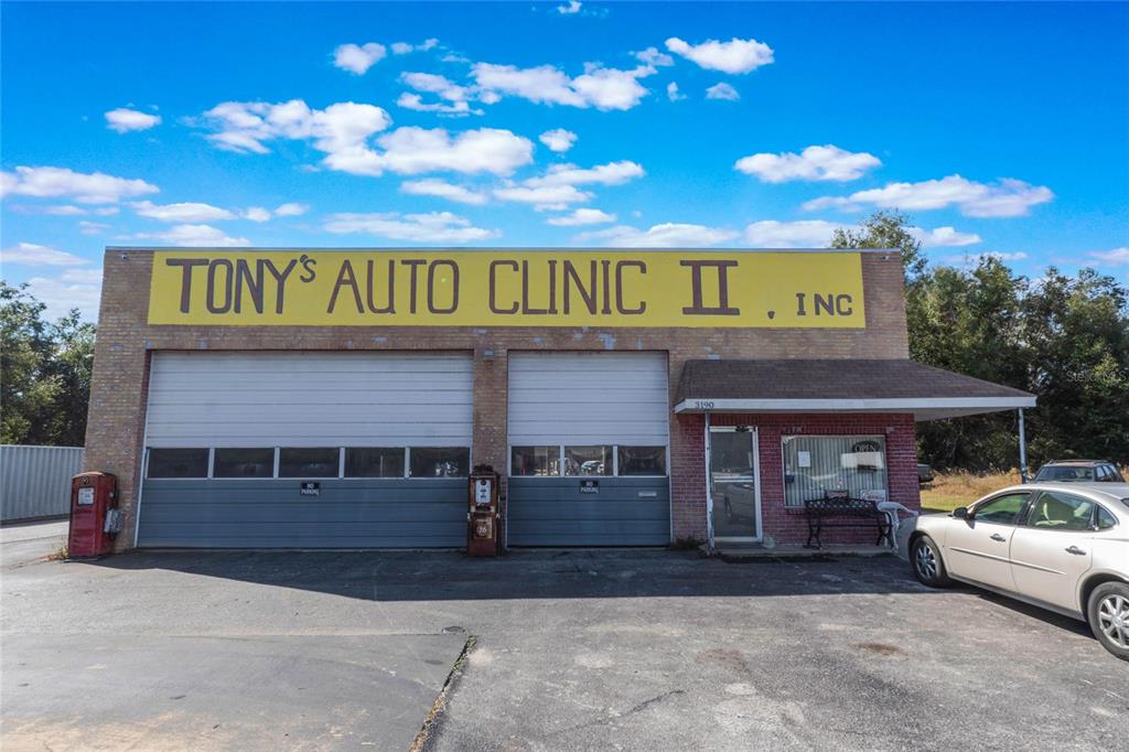 The exterior of a brick auto repair shop features two garage doors and a small office — 3190 S FLORIDA AVENUE, INVERNESS, FL