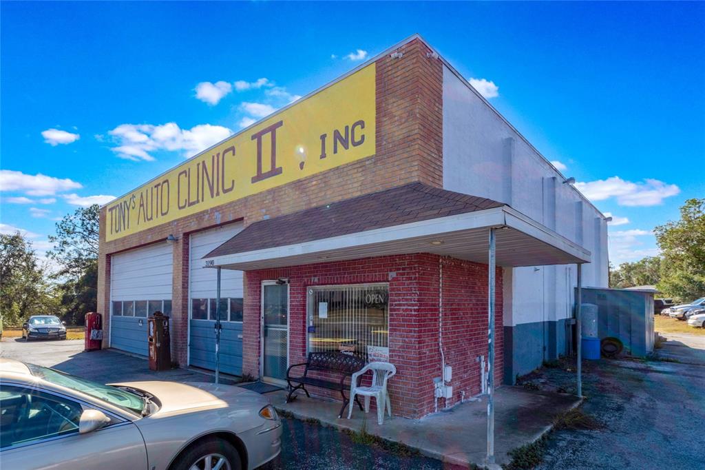 The exterior of a brick auto repair shop features a yellow sign and two garage bays — 3190 S FLORIDA AVENUE, INVERNESS, FL