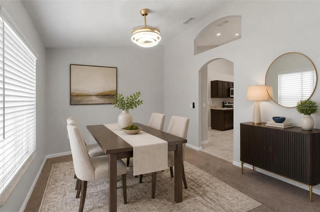 A dining room features a wooden table, upholstered chairs, a sideboard, and a modern light fixture — 12155 PEREGRINE FALCON AVENUE, WEEKI WACHEE, FL