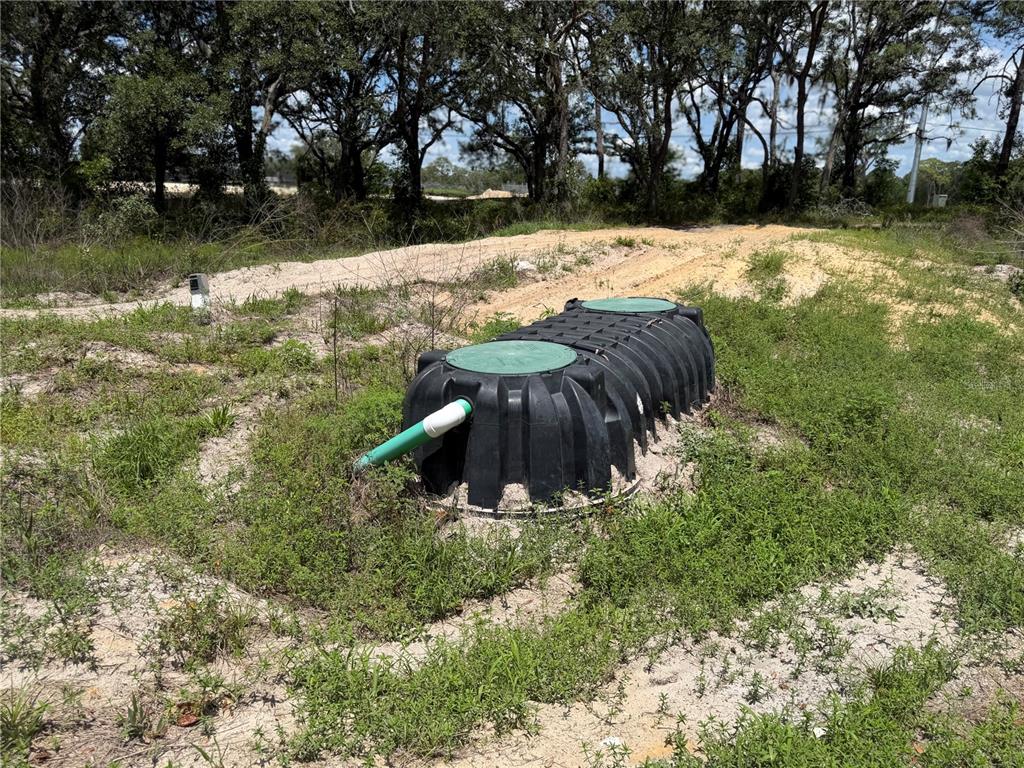 A black plastic septic tank with green lids sits partially buried in a grassy lot — 3310 TREIMAN BOULEVARD, DADE CITY, FL