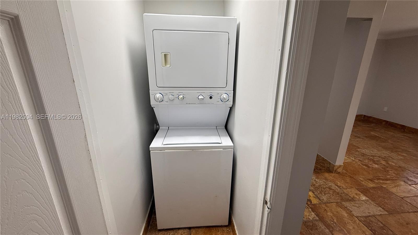 A white stacked washer and dryer unit is installed in a small closet alcove — 1814 Thomas St Rear, Hollywood FL 33020, HOLLYWOOD, FL