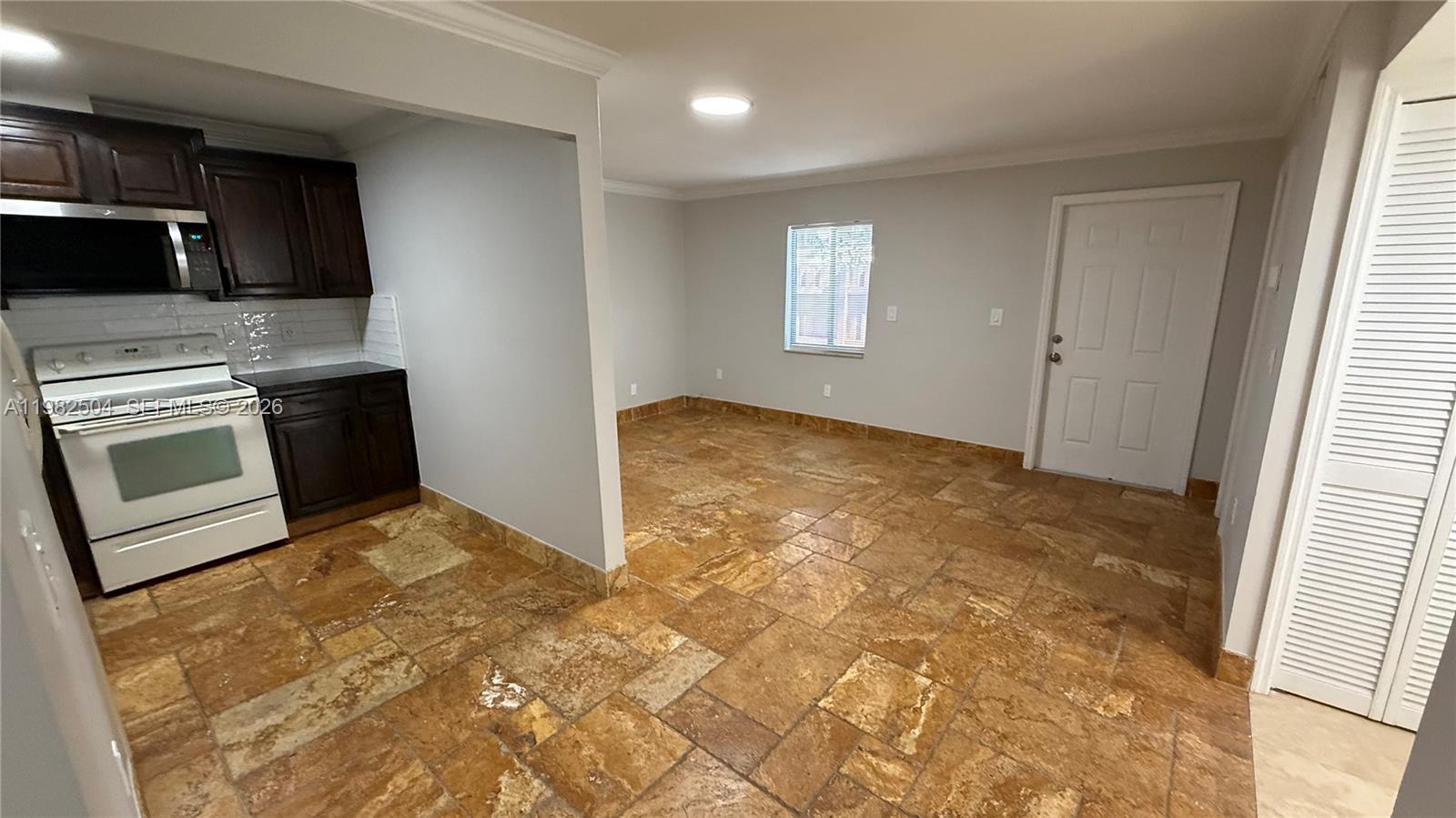A kitchen with dark cabinets and white appliances opens into a tiled dining area — 1814 Thomas St Rear, Hollywood FL 33020, HOLLYWOOD, FL