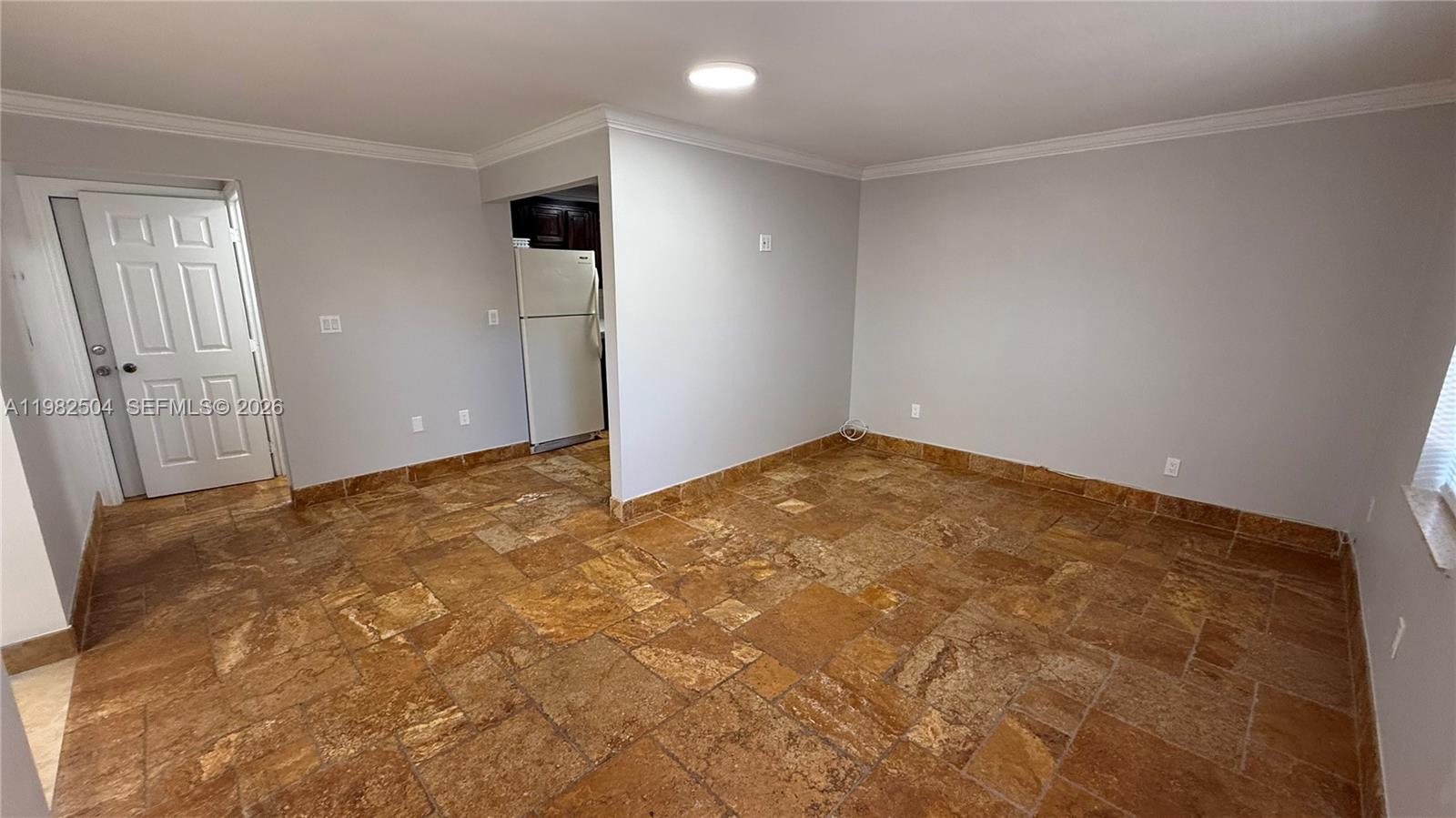 An empty room features light gray walls, crown molding, and brown stone tile flooring — 1814 Thomas St Rear, Hollywood FL 33020, HOLLYWOOD, FL