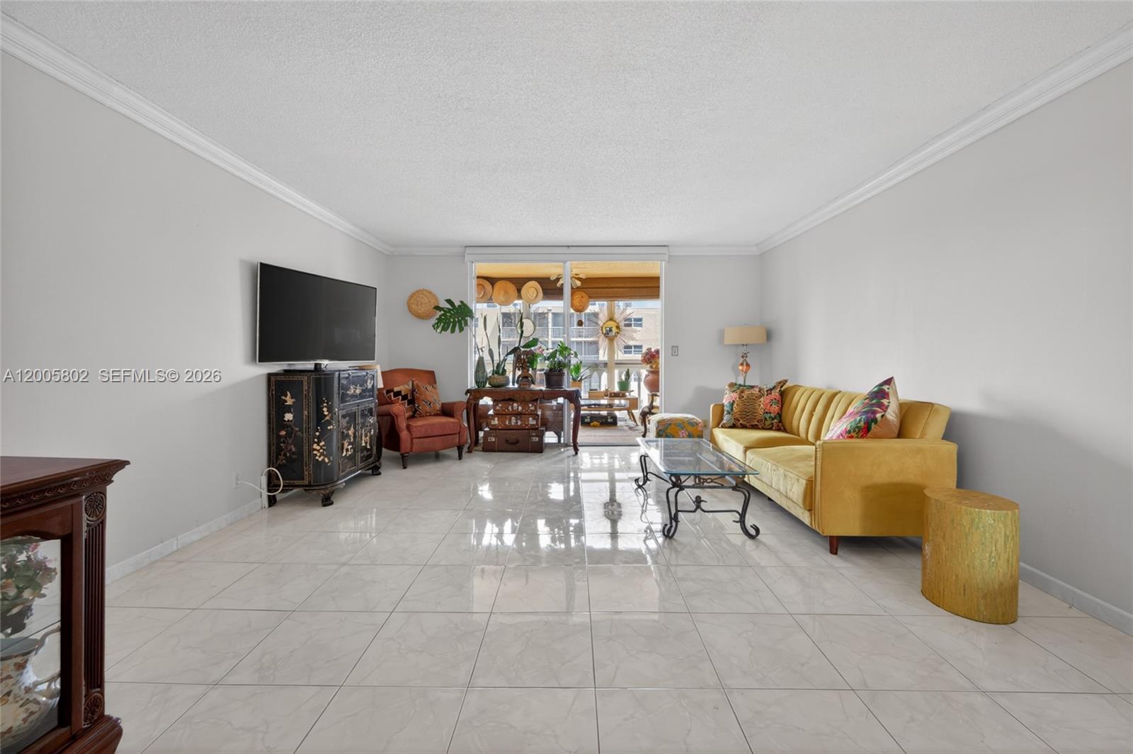 A living room features a yellow sofa, a black cabinet, and tile flooring — 610 NE 12th Ave # 602, Hallandale Beach FL 33009, HALLANDALE BEACH, FL