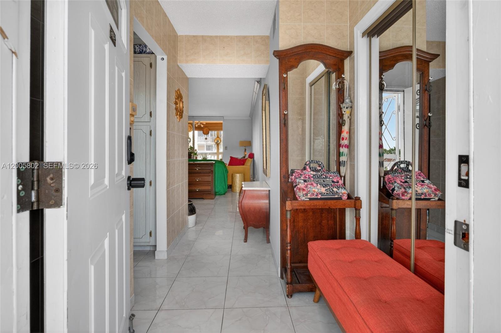 A tiled entryway features a wooden hall tree with a mirror and a red bench — 610 NE 12th Ave # 602, Hallandale Beach FL 33009, HALLANDALE BEACH, FL