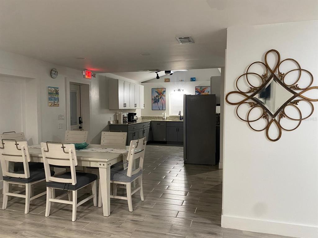 A dining area with a white table and chairs opens into a kitchen with gray cabinets — 9921 VAUGHN STREET UNIT 3 Bd, GIBSONTON, FL