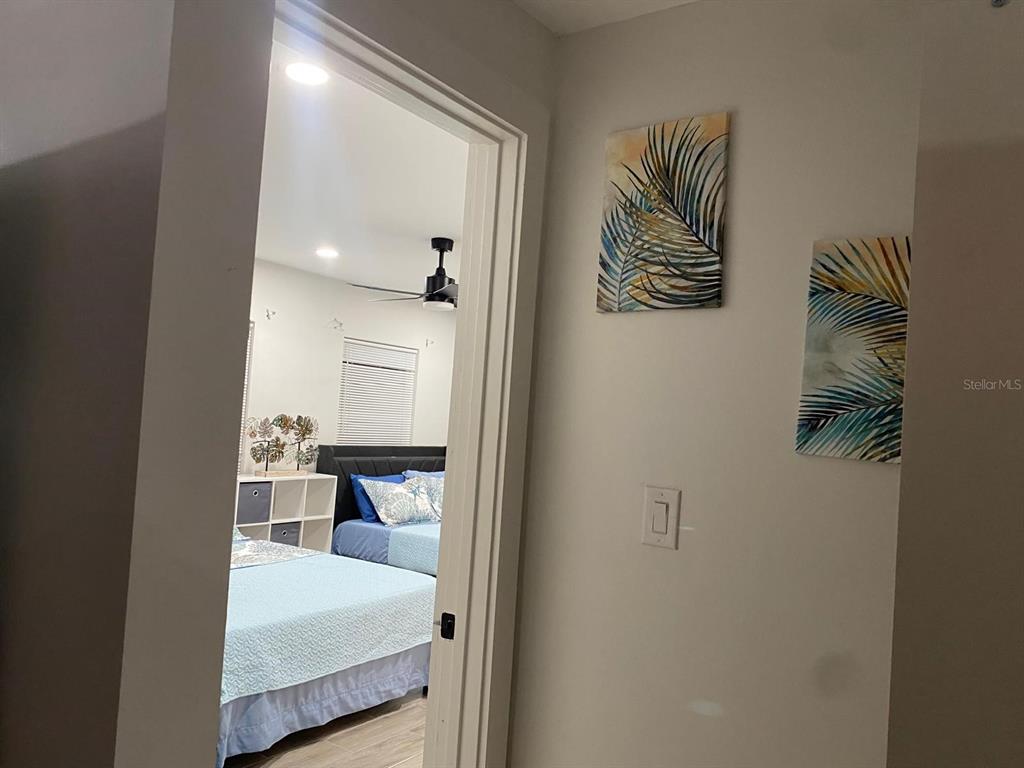 A doorway leads from a hallway with wall art into a bedroom with two beds — 9921 VAUGHN STREET UNIT 3 Bd, GIBSONTON, FL
