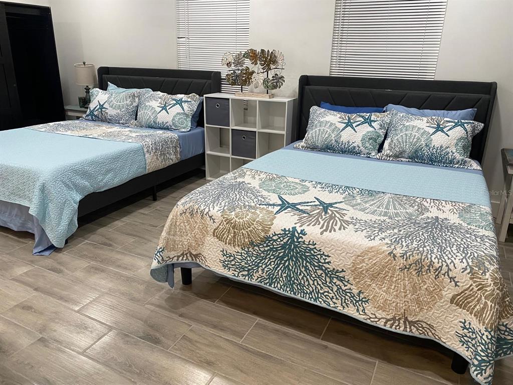 A bedroom features two beds with coastal-themed bedding, a white storage unit, and tile flooring — 9921 VAUGHN STREET UNIT 3 Bd, GIBSONTON, FL