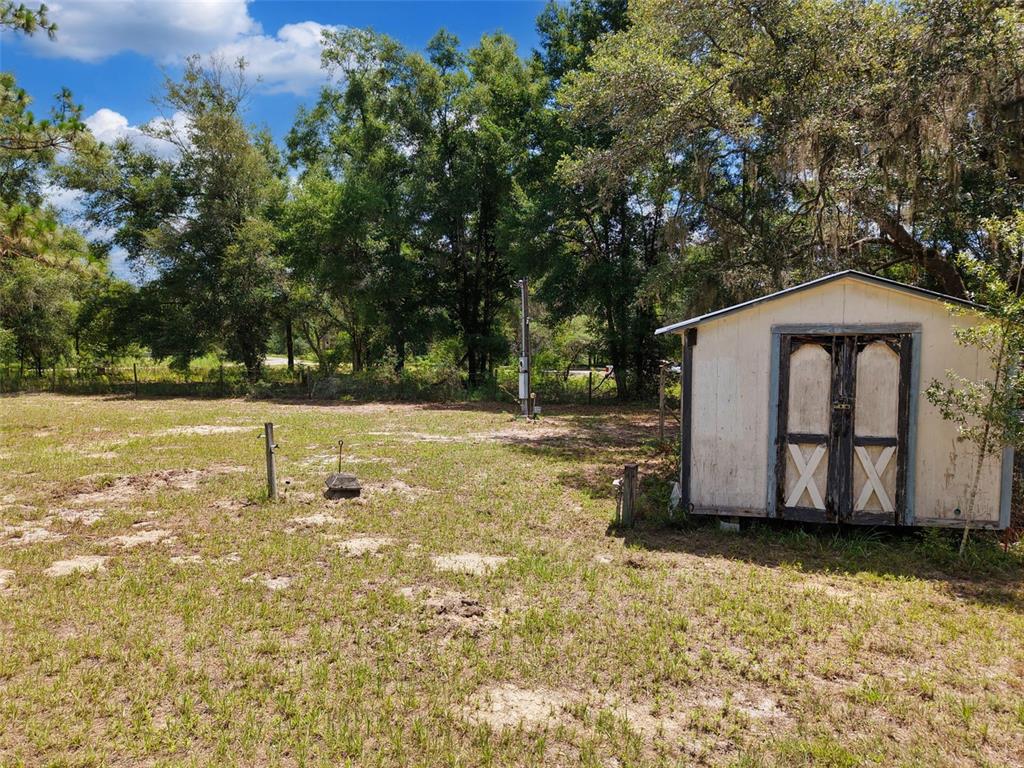 A small storage shed sits on a grassy, partially wooded lot with a utility pole — 54 NE 841ST AVENUE, OLD TOWN, FL