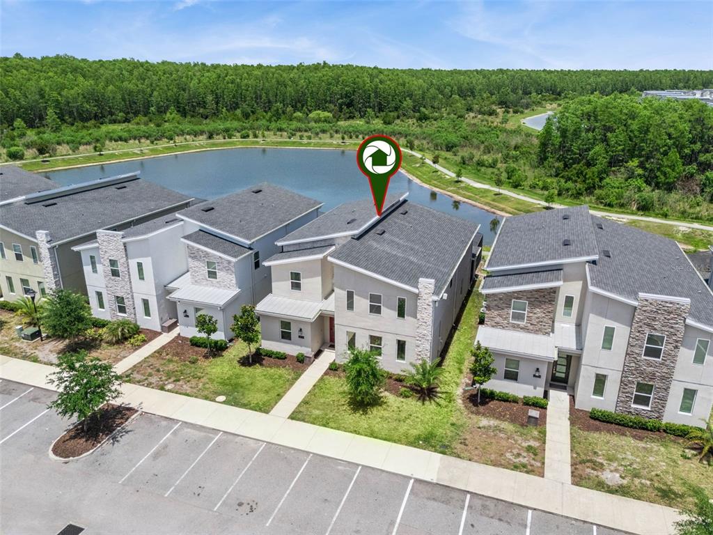An aerial view shows a row of modern townhomes situated next to a pond — 2876 SIMILE STREET, KISSIMMEE, FL