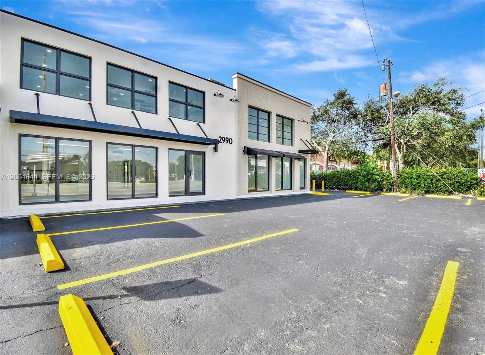 A two-story commercial building with a paved parking lot and yellow wheel stops — 2990 Griffin Rd, Dania Beach FL 33312, DANIA BEACH, FL