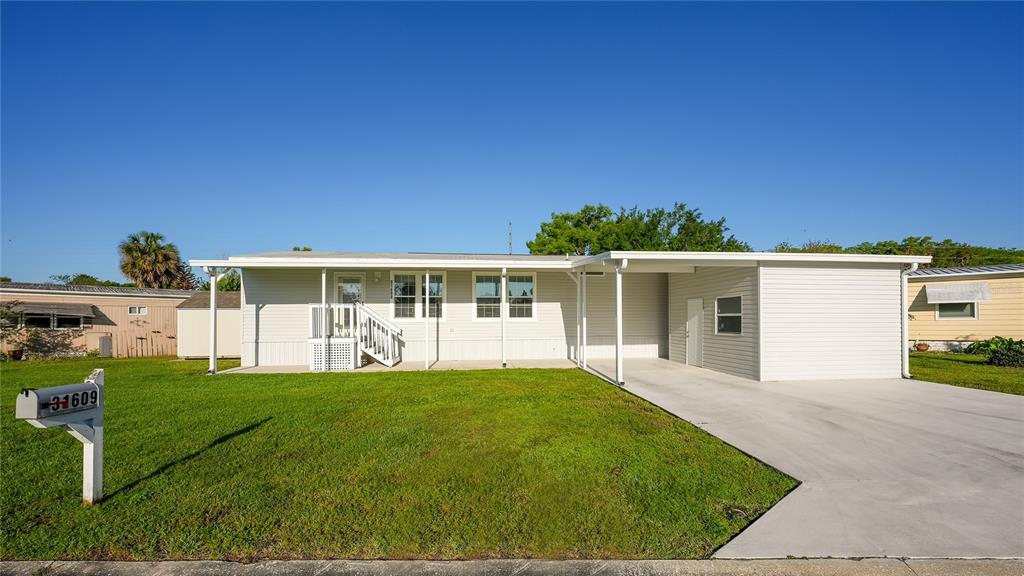 A single-story manufactured home with light siding, a front porch, and an attached carport — 31609 TERRACE DRIVE, TAVARES, FL