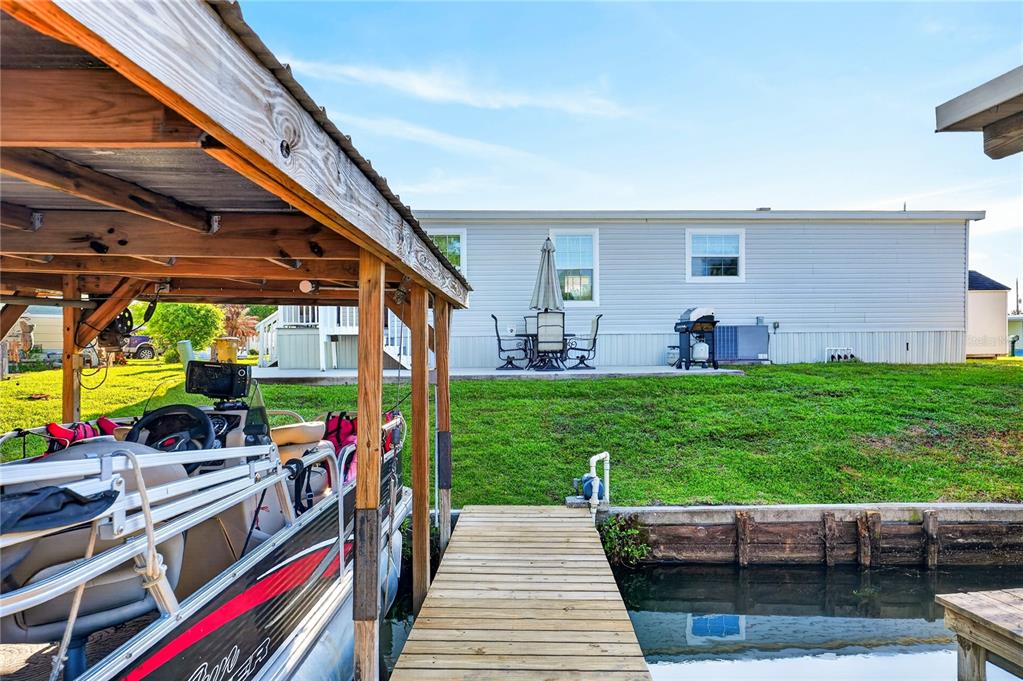 A boat is docked at a wooden pier in front of a house with a patio — 31609 TERRACE DRIVE, TAVARES, FL