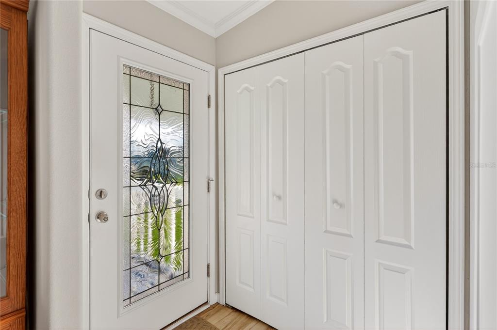 A white front door with a decorative glass insert sits beside a white bifold closet — 31609 TERRACE DRIVE, TAVARES, FL