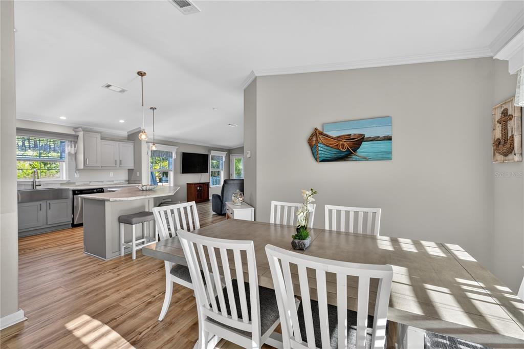 A dining area with a wooden table and white chairs opens to a modern kitchen — 31609 TERRACE DRIVE, TAVARES, FL