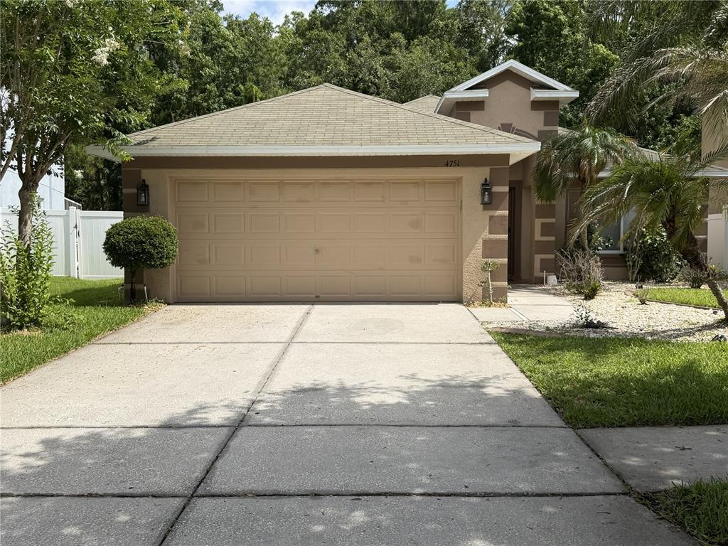 A beige single-story house with a two-car garage and a concrete driveway — 4751 BARCHETTA, LAND O LAKES, FL
