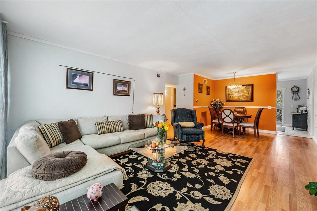 A living room with a sectional sofa, floral area rug, and an adjacent dining area — 5665 40TH AVENUE N UNIT 407, KENNETH CITY, FL