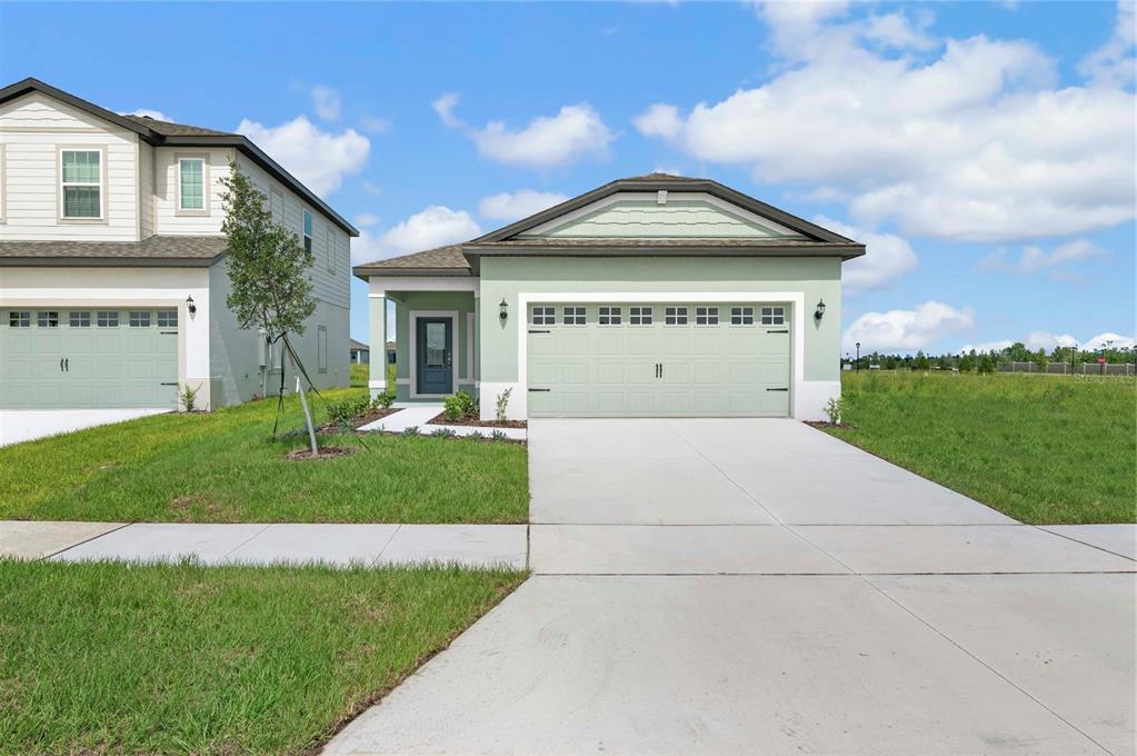 A light green single-story house with a two-car garage and a concrete driveway — 3617 AMANATSU STREET, LAKE ALFRED, FL