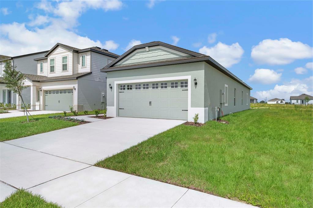A light green single-story house with a two-car garage and a concrete driveway — 3617 AMANATSU STREET, LAKE ALFRED, FL