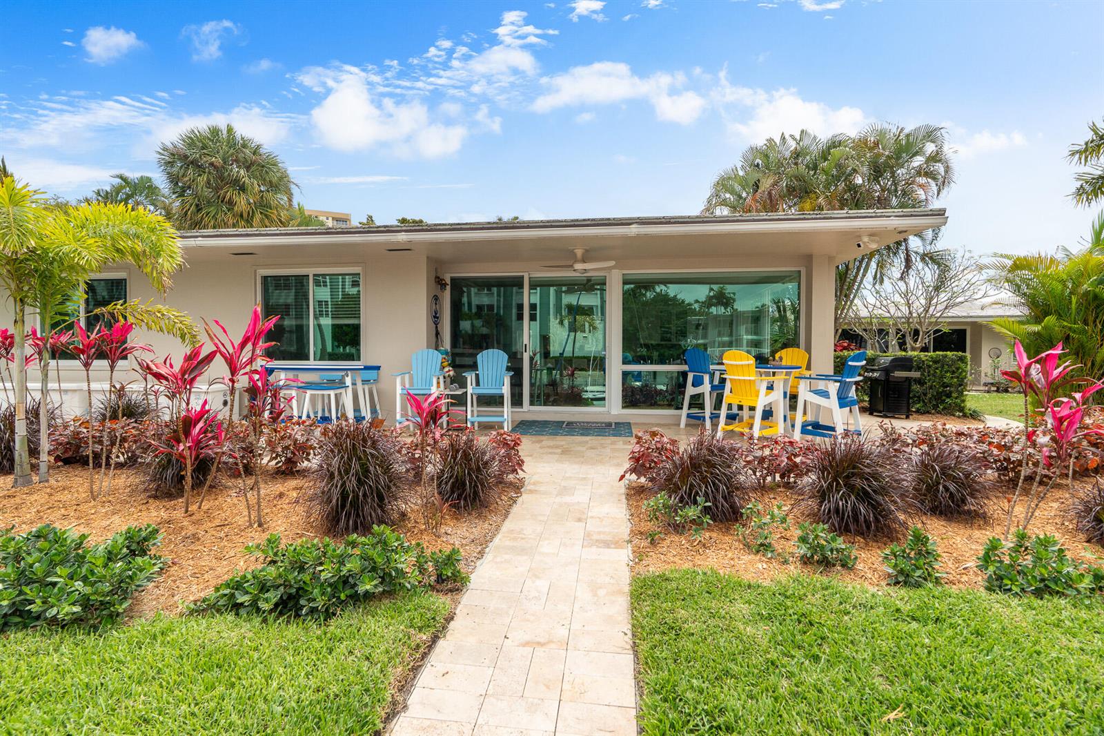 A ground-level patio with colorful chairs and landscaping in front of a house exterior — 3211 SE 11th Street # 3e, Pompano Beach FL 33062, POMPANO BEACH, FL