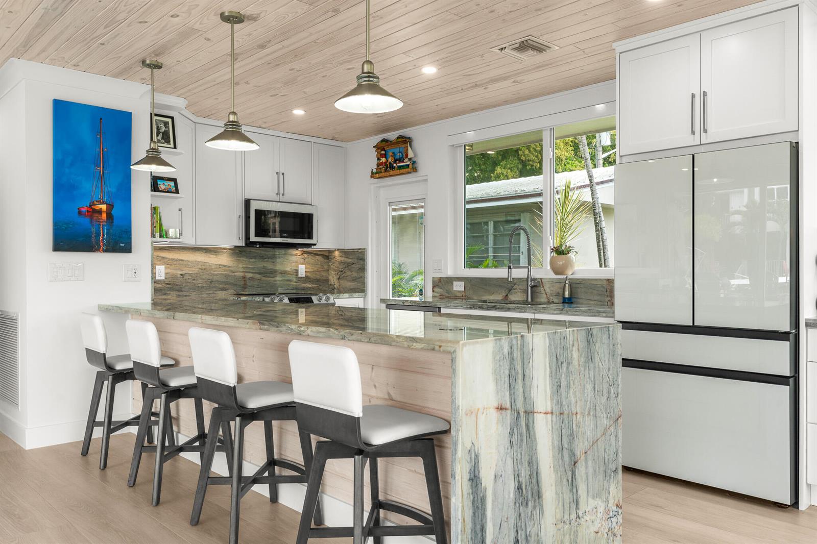 A kitchen features a stone waterfall island, white cabinetry, and a wood-paneled ceiling — 3211 SE 11th Street # 3e, Pompano Beach FL 33062, POMPANO BEACH, FL