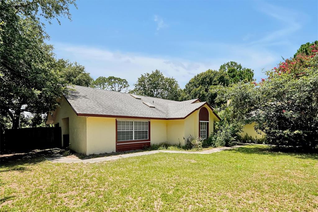 A yellow single-story house with a gray shingled roof and a large front lawn — 3640 WOOD DUCK DRIVE, MIMS, FL