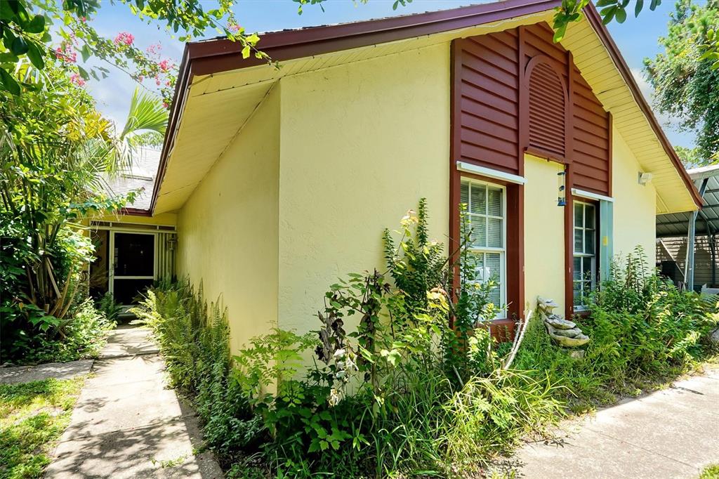 A yellow house exterior features brown trim, a front walkway, and overgrown landscaping — 3640 WOOD DUCK DRIVE, MIMS, FL