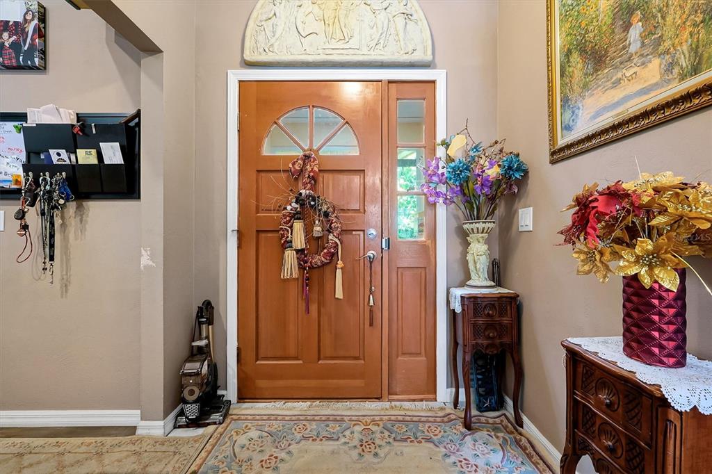 An entryway features a wooden front door, a decorative wall relief, and floral arrangements — 3640 WOOD DUCK DRIVE, MIMS, FL