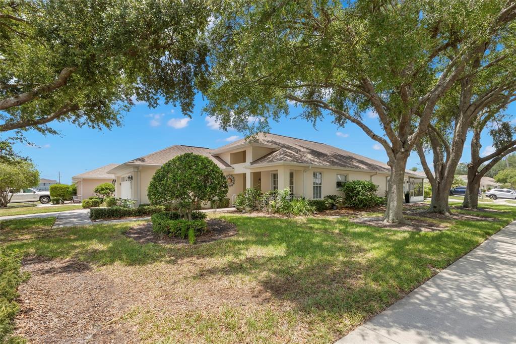A single-story house with a tan exterior, a shingled roof, and large trees in front — 14023 SHOAL DRIVE, HUDSON, FL