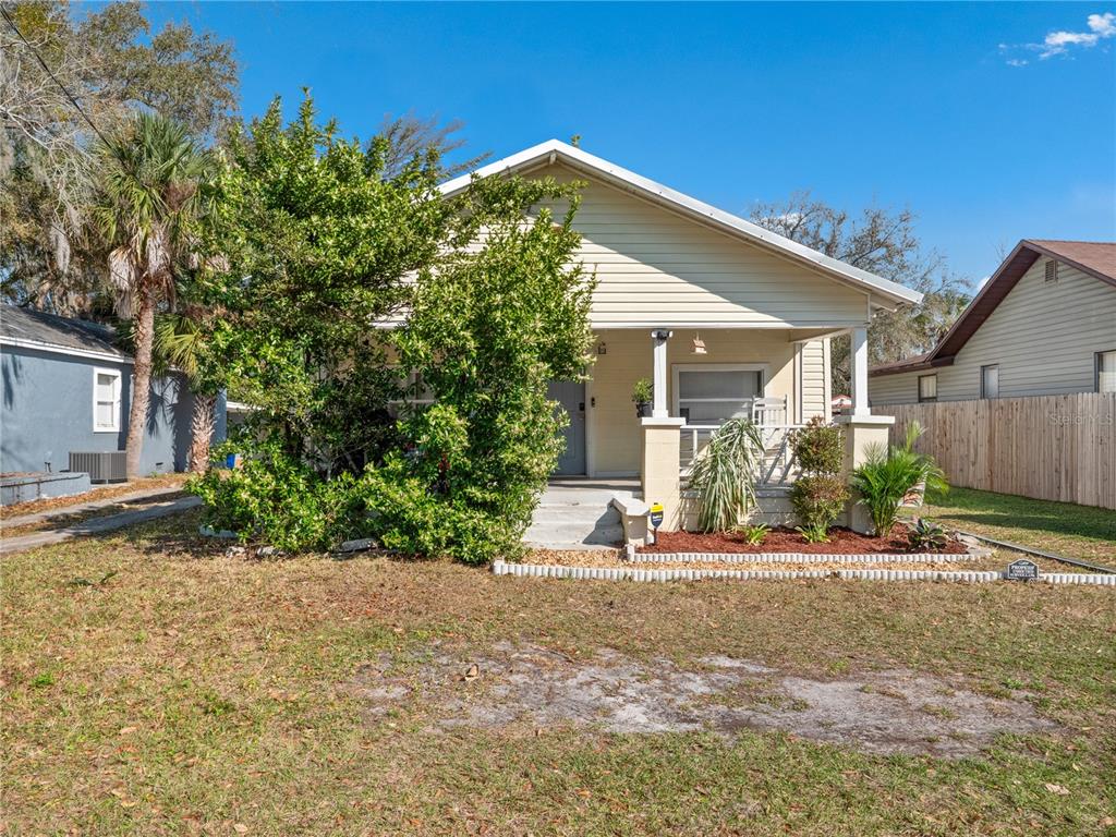 A single-story house with light yellow siding, a front porch, and a large green bush — 1208 W 10TH STREET, SANFORD, FL