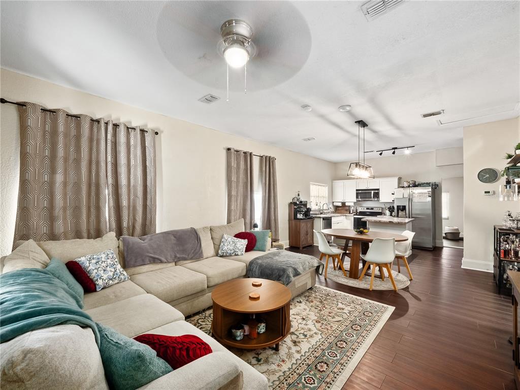 An open-concept living room and kitchen featuring a sectional sofa, dining area, and hardwood floors — 1208 W 10TH STREET, SANFORD, FL