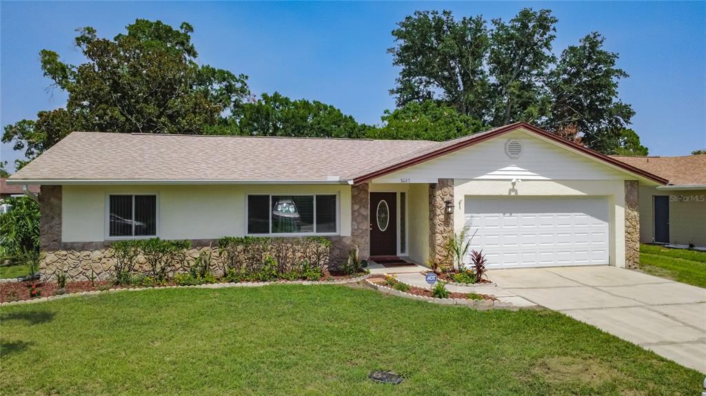 A single-story house with a stone facade, a white garage door, and a front lawn — 5225 ALBERT DRIVE, WINTER PARK, FL