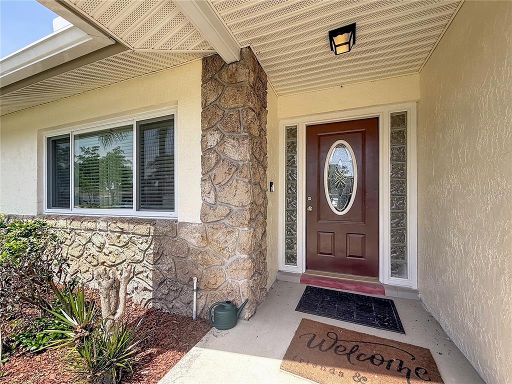 A front entrance features a brown door with glass inserts, stone siding, and a welcome mat — 5225 ALBERT DRIVE, WINTER PARK, FL