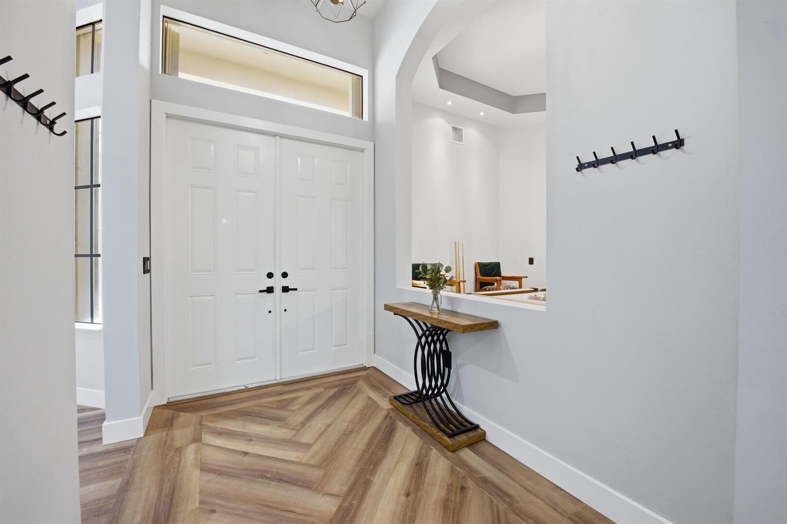 An entryway features a white double door, herringbone wood flooring, and a decorative console table — 6983 Antinori Lane, Boynton Beach FL 33437, BOYNTON BEACH, FL