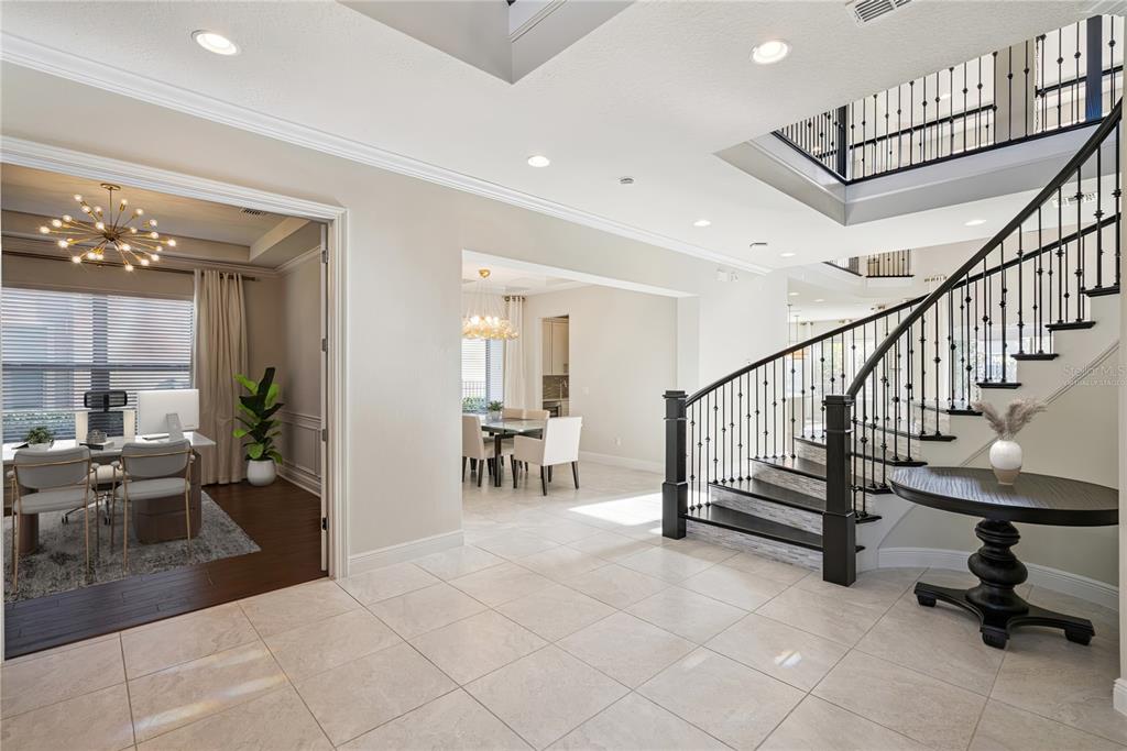 A foyer features a curved staircase with iron railings, tile flooring, and adjacent dining areas — 8591 ADALINA PLACE, ORLANDO, FL